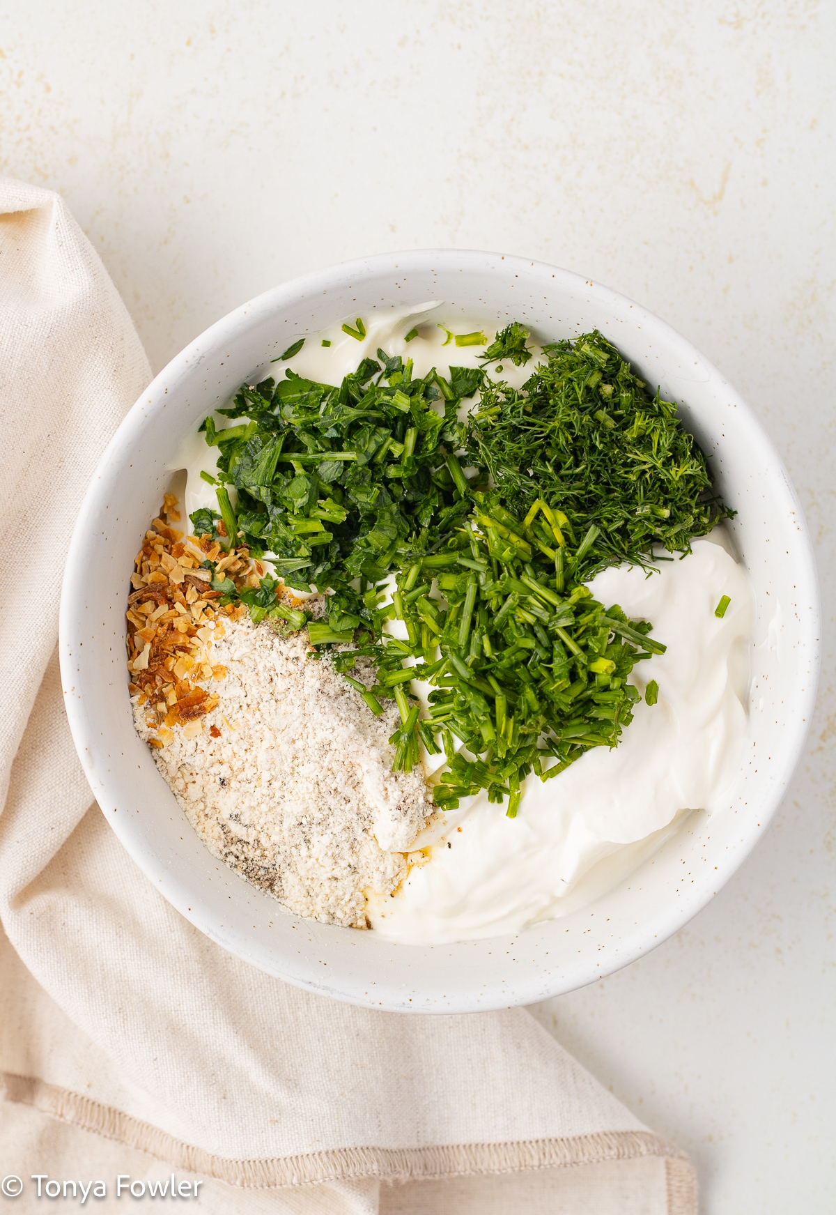 Seasonings and herbs in a bowl with sour cream and mayo.