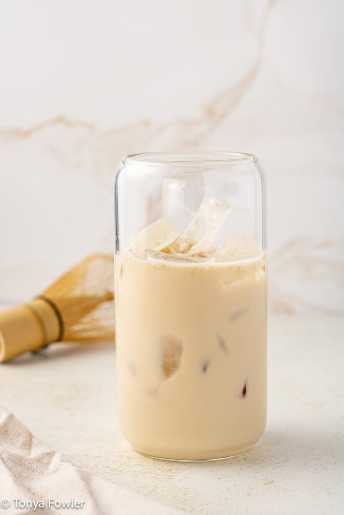 Straight on view of protein powder mixed with oatmilk in a glass with ice.