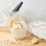 A scoop of Ninja Creami Vanilla Protein Ice Cream in a glass topped with sprinkles and cookies.