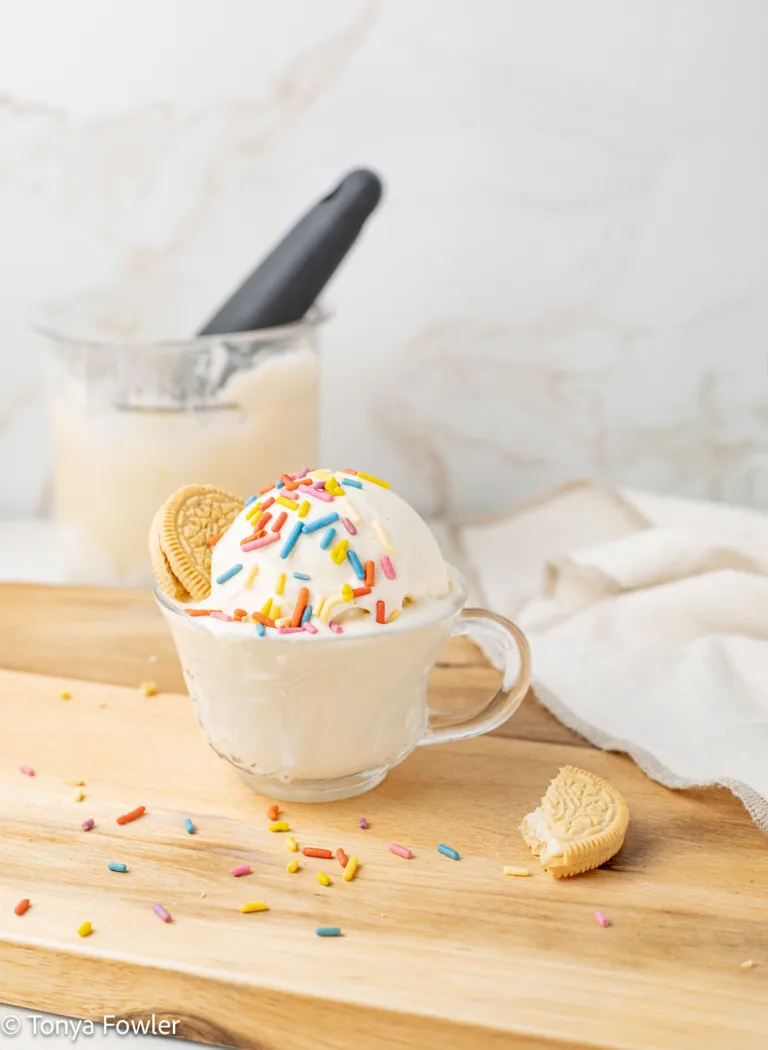 A scoop of Ninja Creami Vanilla Protein Ice Cream in a glass topped with sprinkles and cookies.