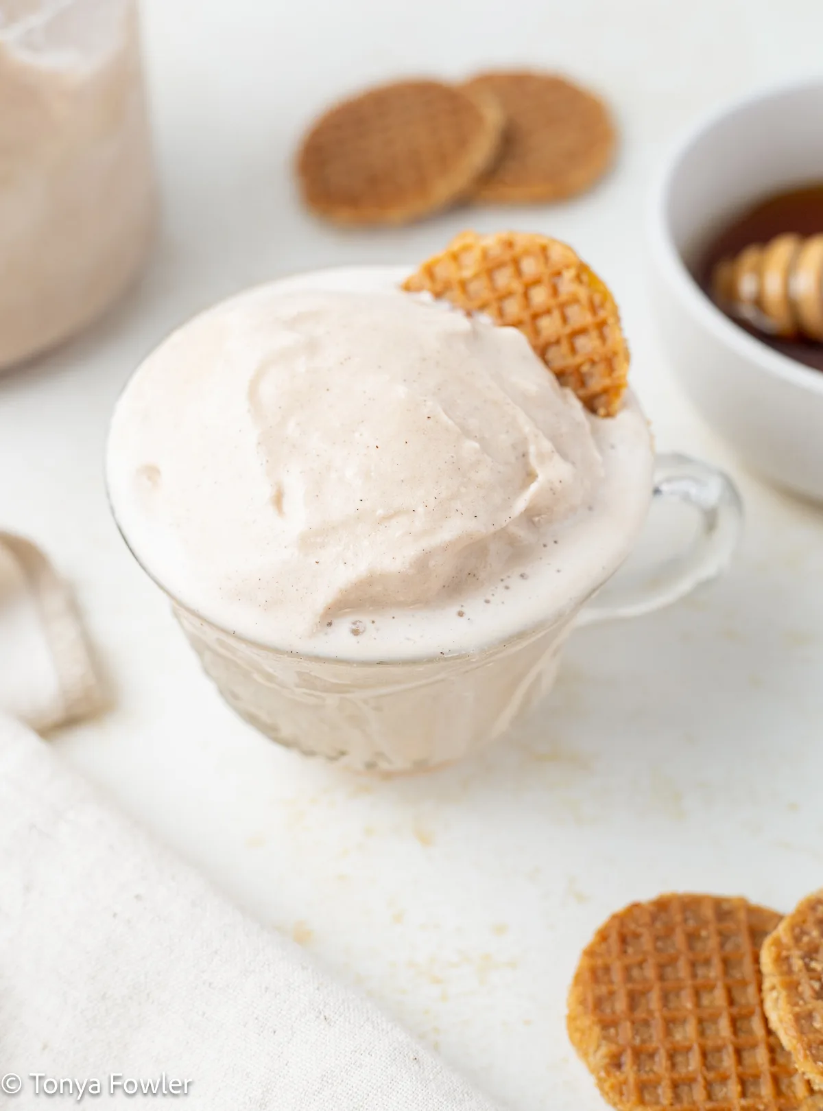A scoop of ice cream in a glass topped with a honey wafer.
