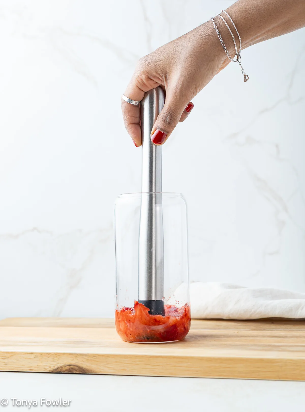Strawberries being mashed with a cocktail muddler.