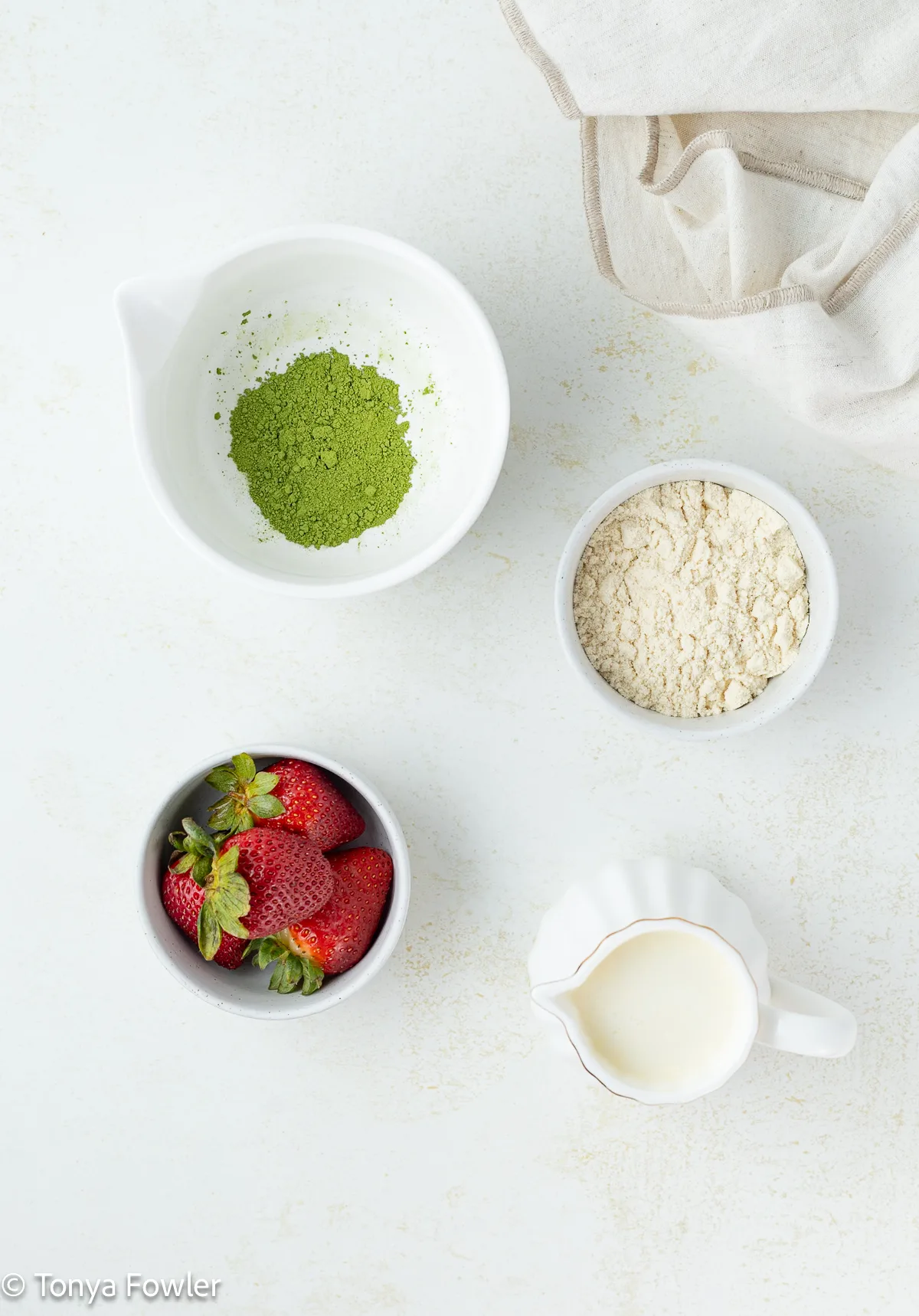 Ingredients for strawberry protein matcha latte on a counter.