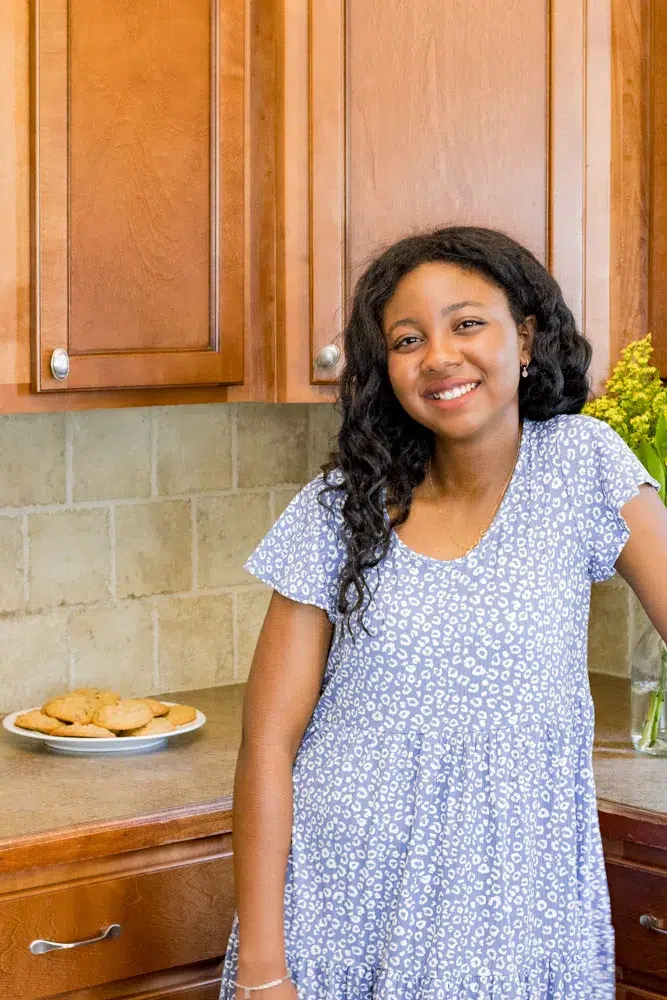 Profile image. Woman in a blue dress posing by a plate of cookies.
