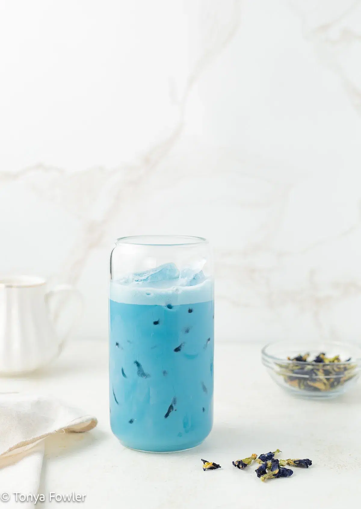 Straight on view of a blue matcha latte in a glass with ice.